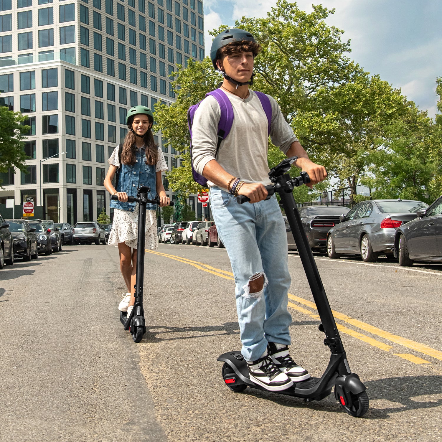 two young people riding the Rhythm e-scooter through the streets