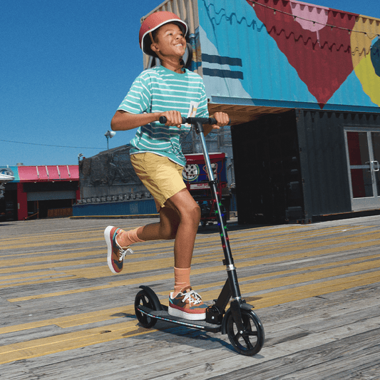 kid riding black jupiter jumbo scooter on a boardwalk